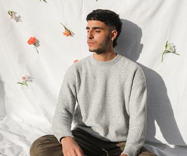 Person sitting in a calm meditation pose by a sunlit window.